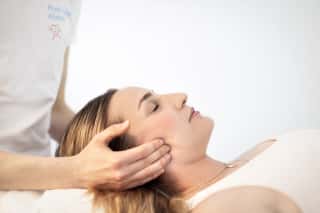 Physiotherapeut führt Kieferphysiotherapie an Patientin durch